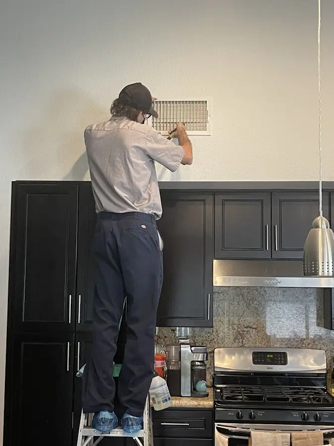 Technician inspecting an air vent during HVAC service in Hartselle
